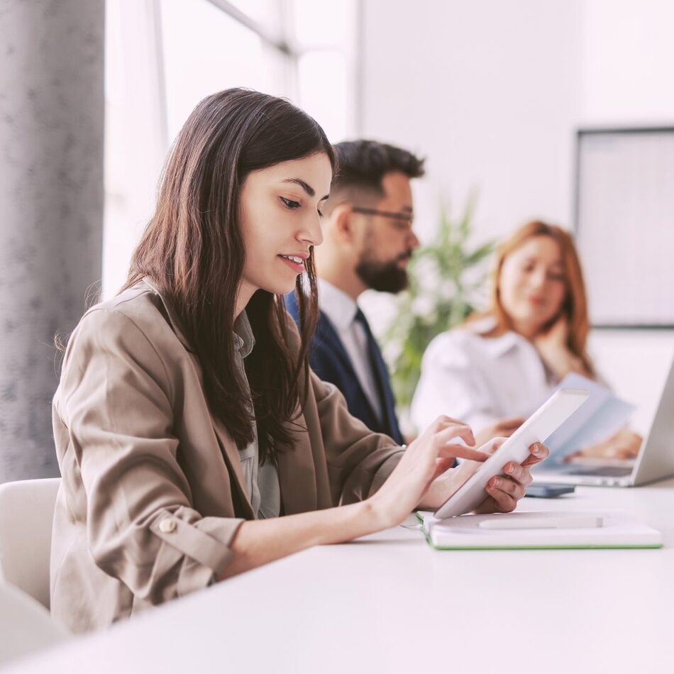 Young professional woman using a tablet during a meeting in a bright office setting.