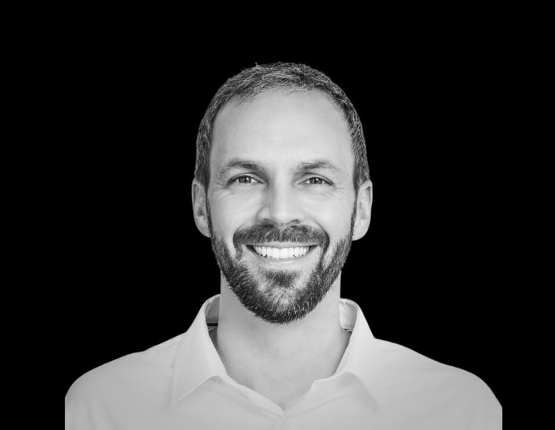 Portrait of Jay Ure, Director of Customer Success at Prevu3D, smiling and wearing a light-colored shirt against a solid black background.