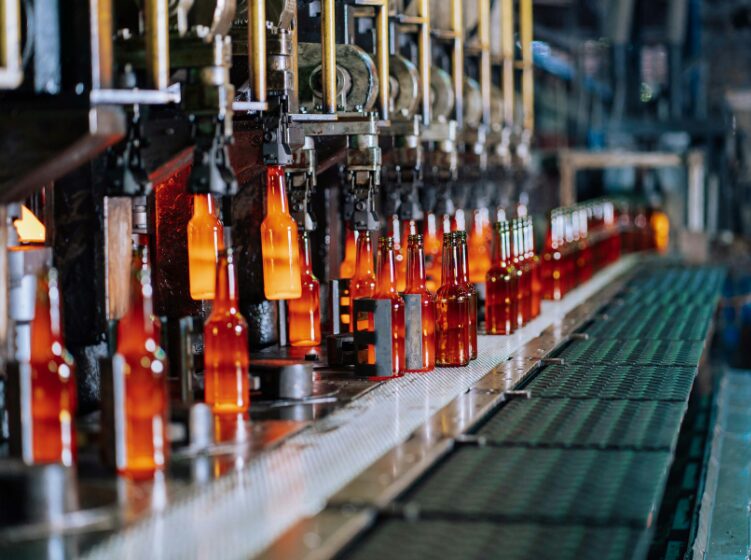 Bottling line with orange glass bottles moving along a conveyor in a factory setting